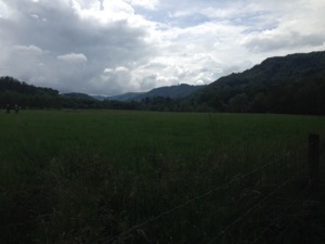 View over dark fields under cloudy sky.