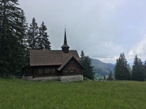 Small wooden chappel on top of an alpine meadow