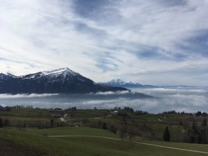 Rigi in the background, cloud filled valleys in midground, and green fields in foreground.