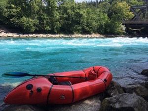 Red packraft in front of turquoise river Aare.