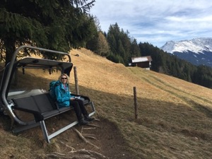 Jules sitting on a ski-lift chair, looking out over the Voralberg valley