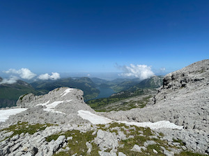 View down over the Wägitalersee from near the peak of Mutteristock, under bright deep blue skies.