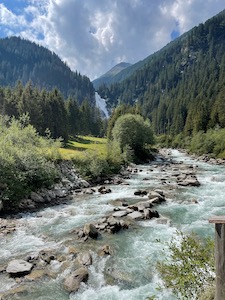 Top section of the Krimml waterfall, under partially cloudy skies.