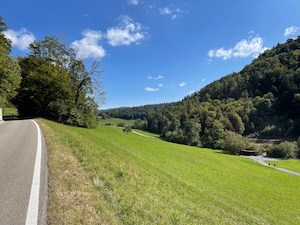 Cycling above a green valley under blue skies.