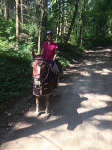 Girl on horseback on a gravel road in trees