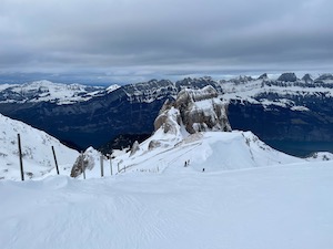 Ski piste with craggy, snow capped mountains in the background.