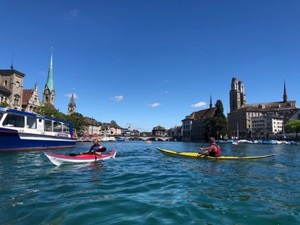 Two sea-kayaks on the Limmat, with Zurich city centre in the background.