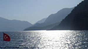 Silhouette of mountains and sun reflecting off sea