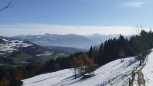 Light snow cover on hillside, moutains in the distance hazy blue skies.