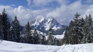 View over the Kleine Mythen in sunshine, with snow tracks in the foreground