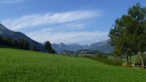 View down the Gruyères valley - green fields framed by mountains.