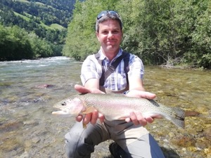 Holding a rainbow trout, in the river.